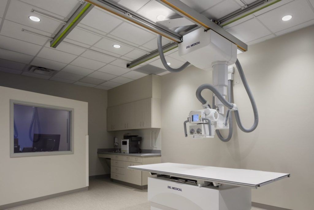 Modern medical X-ray imaging room with advanced equipment and clean white surfaces.